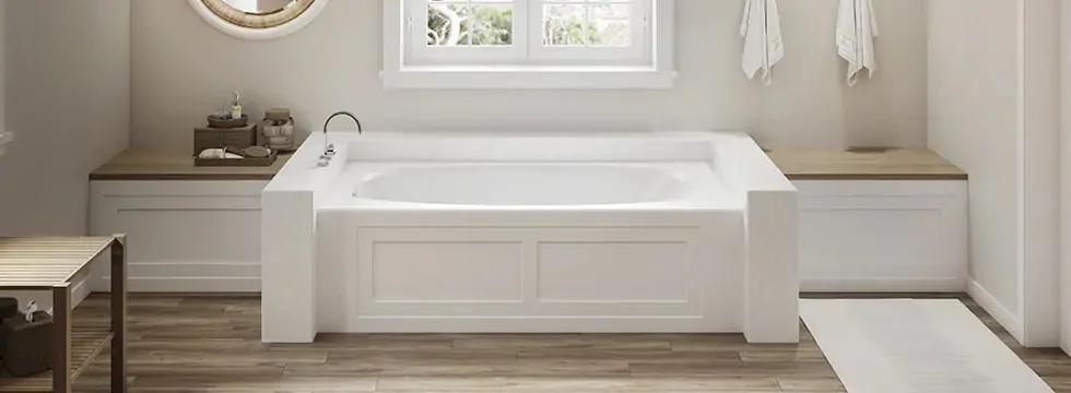 Image of a white tub that has two side benches, a table to the left of the tub in a large bathtroom.