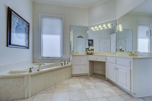 An image of a bathroom with a large vanity, mirrors and a drop in tub.